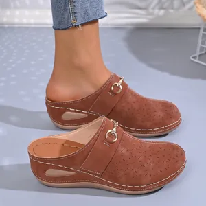 Detailed side view of brown wedge mules featuring laser-cut patterns and metal buckle