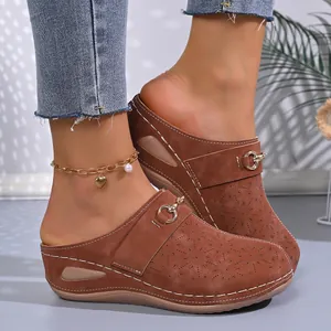 Detailed view of women's brown wedge clogs with floral laser-cut patterns and metal buckle