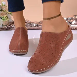 Detailed view of women's brown laser-cut wedge mules featuring elegant floral patterns