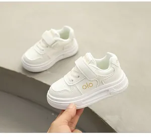 Nahaufnahme von weißen Kinder-Sneakern mit dicken Sohlen und goldenem olo-Muster