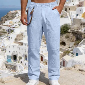 Casual light blue loose linen trousers for men featuring an elastic waist in a scenic outdoor setting.
