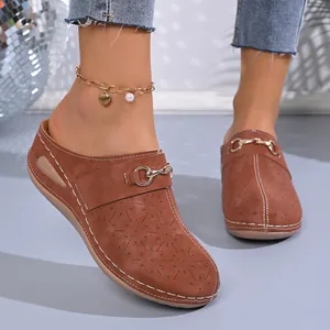 Detailed view of women brown leather mules with laser-cut floral patterns and metal horsebit
