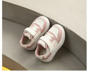 Detailansicht von oben auf rosa-weiße Kindersneaker mit Klettverschluss auf Betontreppen