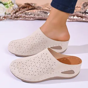 Close-up of beige platform mule slippers with decorative laser-cut floral patterns