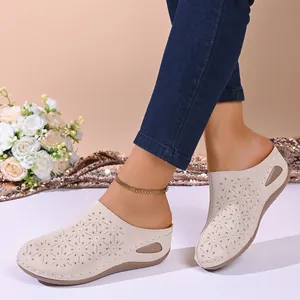 Detailed side view of women's beige laser-cut wedge mules with floral patterns