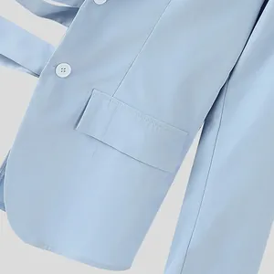 Dettaglio di un blazer da uomo azzurro con una tasca elegante e un bottone bianco