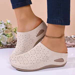 Detailed view of women's beige wedge clogs featuring a laser-cut floral pattern