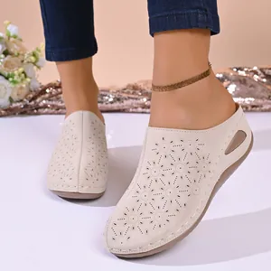 Close-up detail of beige women's laser-cut floral loafers with a comfortable wedge heel.