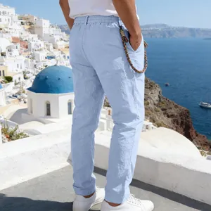Back view of men's loose light blue linen casual pants in a scenic outdoor setting.