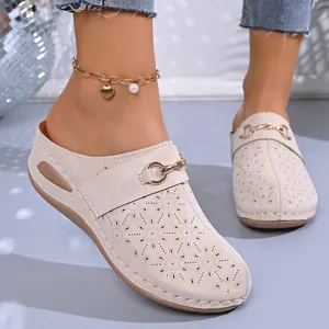 Detail of women's beige platform wedge mules with decorative floral hollow-out patterns.