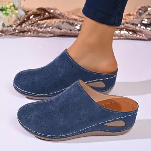 Close-up of blue wedge clogs with floral laser-cut details and white contrast stitching