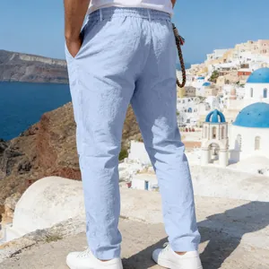 Rear view of men's light blue linen casual pants with Santorini background scene.