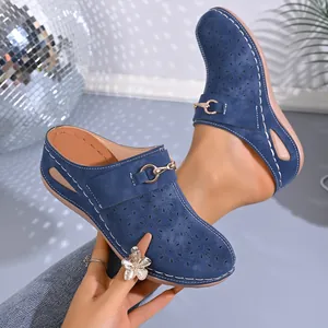 Detailed view of blue wedge mules with laser-cut floral patterns and metal buckle.
