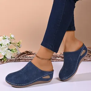 Close-up of navy blue perforated closed-toe mules with platform sole on model feet.