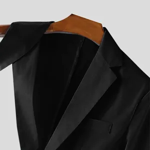 Dettaglio di un moderno blazer nero da uomo con scollo a rever e trama liscia.