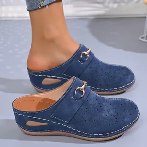 Close-up of blue wedge clogs for women with floral laser-cut patterns and buckle