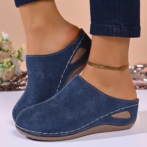 Detailed view of navy blue platform mules with laser-cut floral pattern and stitching