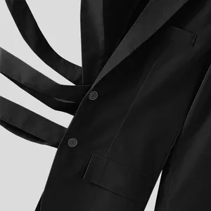 Dettaglio ravvicinato di un blazer nero da uomo con design a cinghie incrociate