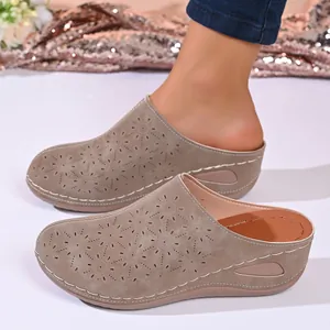 Close-up of women's stylish wedge clogs featuring a hollow floral pattern and thick sole