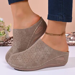 Detailed view of women's taupe wedge clogs featuring laser-cut flower designs and thick soles