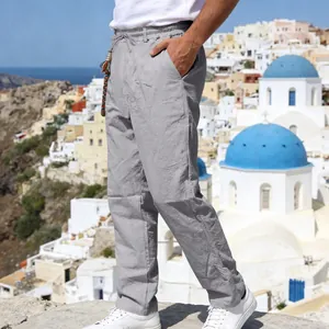 Men's loose grey linen trousers shown in a scenic outdoor Mediterranean setting