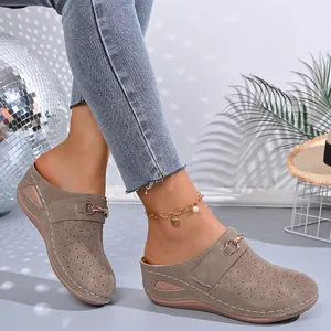 Close-up of women's wedge clogs with hollowed-out floral patterns and metallic buckles.