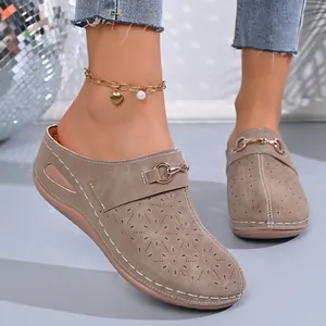 Detailed view of women's wedge mules featuring laser-cut floral patterns and metal buckle