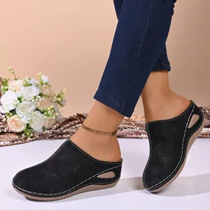 Close-up of black hollow-out wedge mules with floral patterns and contrast stitching