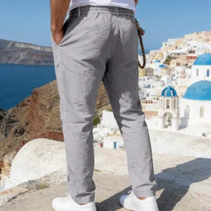 Back view of men's loose grey linen straight-leg trousers in a scenic Greek setting
