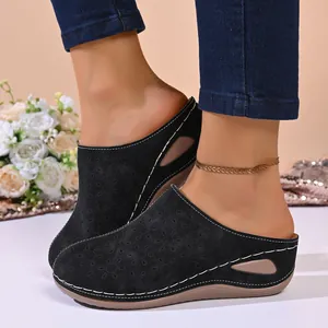 Close-up of black closed-toe mules with laser-cut floral patterns and wedge soles