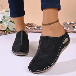Detail view of women's black closed-toe platform mules with floral laser-cut patterns.
