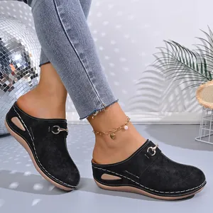 Side detail of black closed-toe wedge slippers featuring white stitching and gold buckle