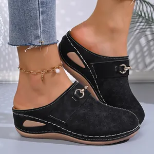Detail view of black wedge mules with floral cutouts and metal buckles