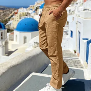 Detail of men's loose tan linen casual pants shown in a scenic Mediterranean setting