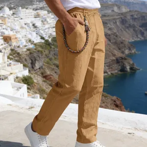 Detailed side view of men's mustard linen loose trousers in a scenic coastal setting