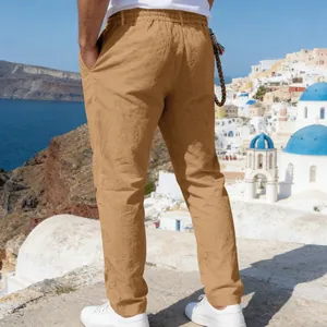 Back view of men's loose linen casual straight pants in camel color at coastal town