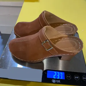 Gedetailleerd overzicht van bruine suède muiltjes op een weegschaal met een gewicht van 239 g.