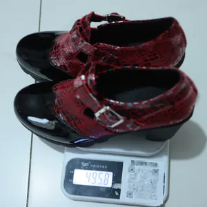 Báscula digital que muestra el peso de 495,8 g de los zapatos de tacón de serpiente