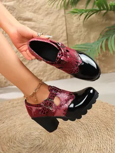 Vista detallada de zapatos de tacón bloque en charol negro y estampado serpiente rojo