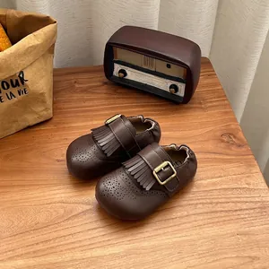 Detailopname van bruine vintage lederen kinderschoenen met franjes en metalen gesp