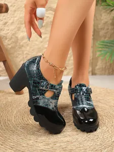 Detalle de zapatos de plataforma en charol negro y piel de serpiente verde azulado