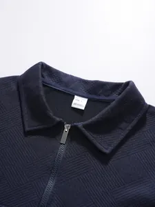 Detail view of navy blue textured jacquard polo shirt with half-zip and collar tag
