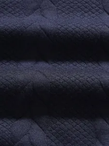 Close-up of navy blue men's polo shirt fabric showing intricate diamond jacquard texture.