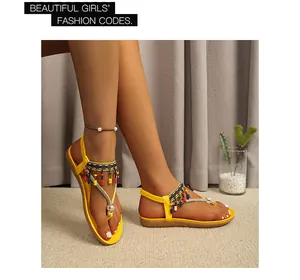 Yellow bohemian flat sandals with colorful beads and rhinestones worn by a model