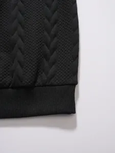 Close-up detail of premium textured jacquard knit fabric on black men's polo shirt hem