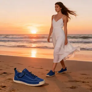Lifestyle-Detail von blauen mittelhohen Lederstiefeln mit Nähten am Strand bei Sonnenuntergang.
