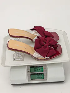 Detailed view of elegant wine red bow high heel sandals being weighed on a scale.