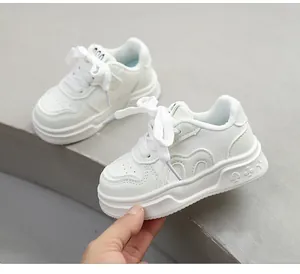 Nahaufnahme von weißen Kinder-Modersneakern mit dicken Sohlen und Ziermustern.