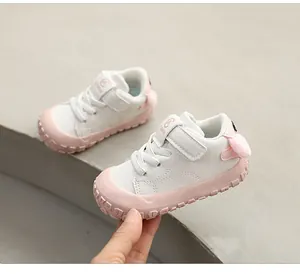 Macro detail view of stylish white and pink baby walking shoes with flexible soft soles.