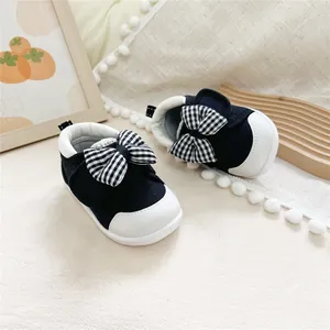 Detail view of Mori-style baby walking shoes featuring a black and white checkered bow.